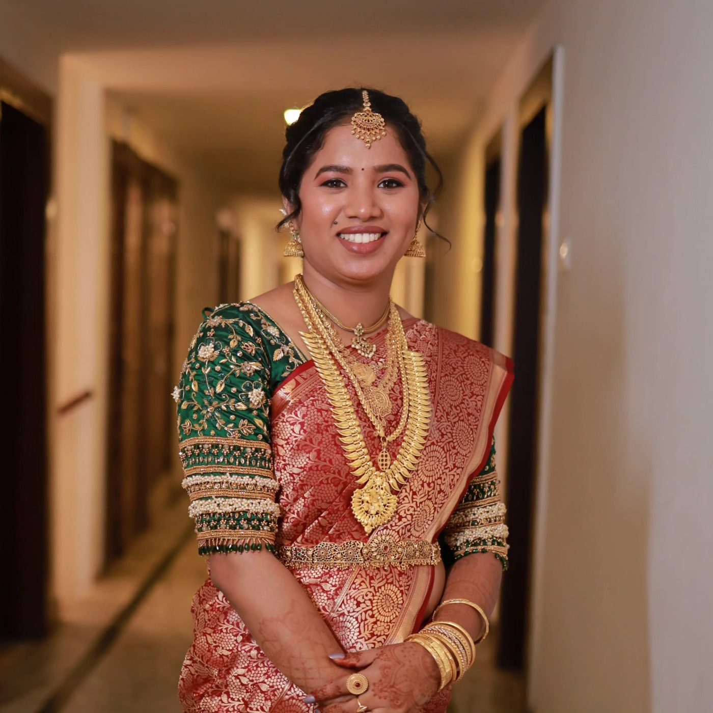 Bride in green and red saree with gold necklace