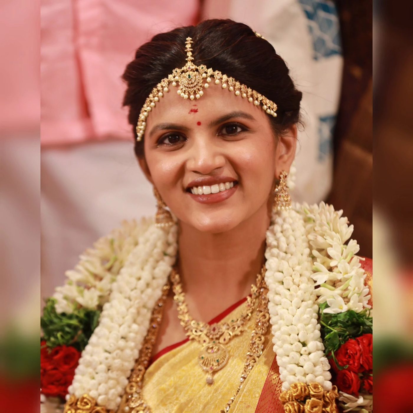 Bride smiling with jasmine garland and maang tikka
